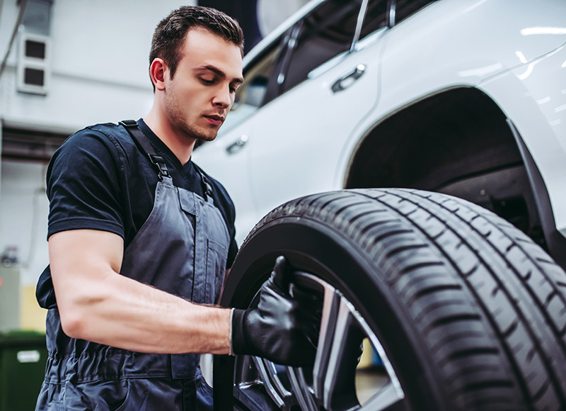 A certified maintenance specialist at GMC is changing a tire on an SUV