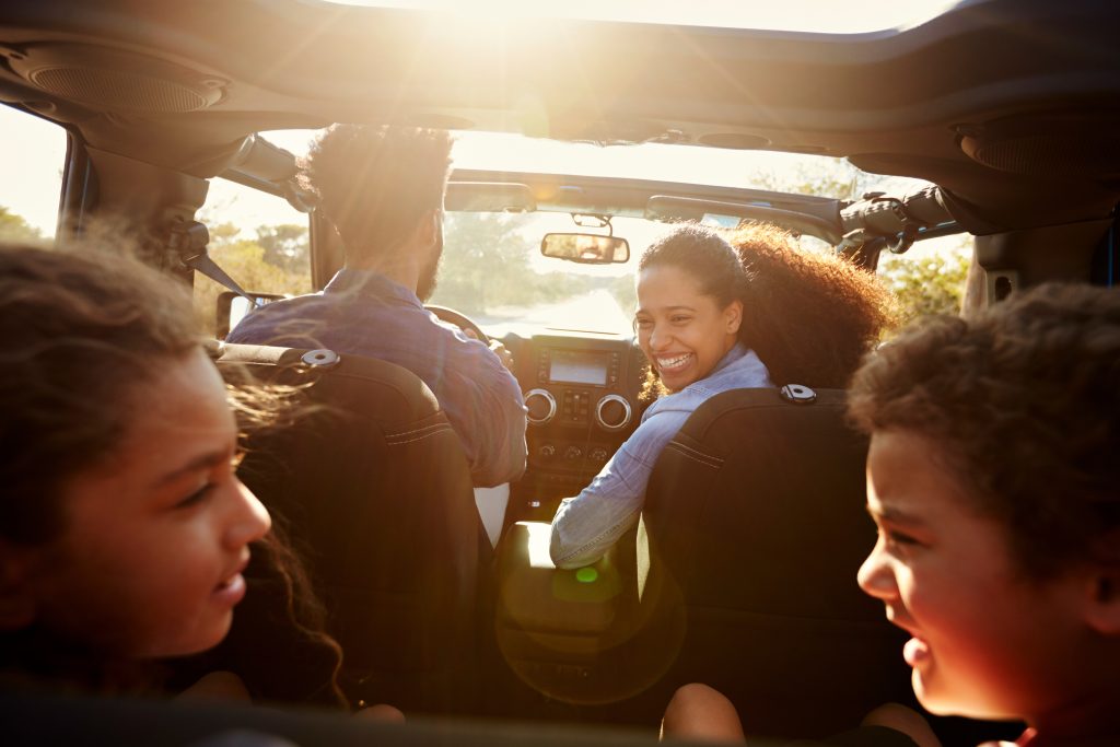 A smiling family is on a road trip in a GMC SUV